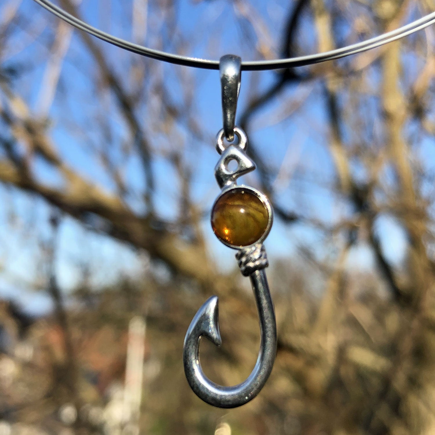 Kleiner Silberanhänger in Form eines Angelhakens mit Bernstein