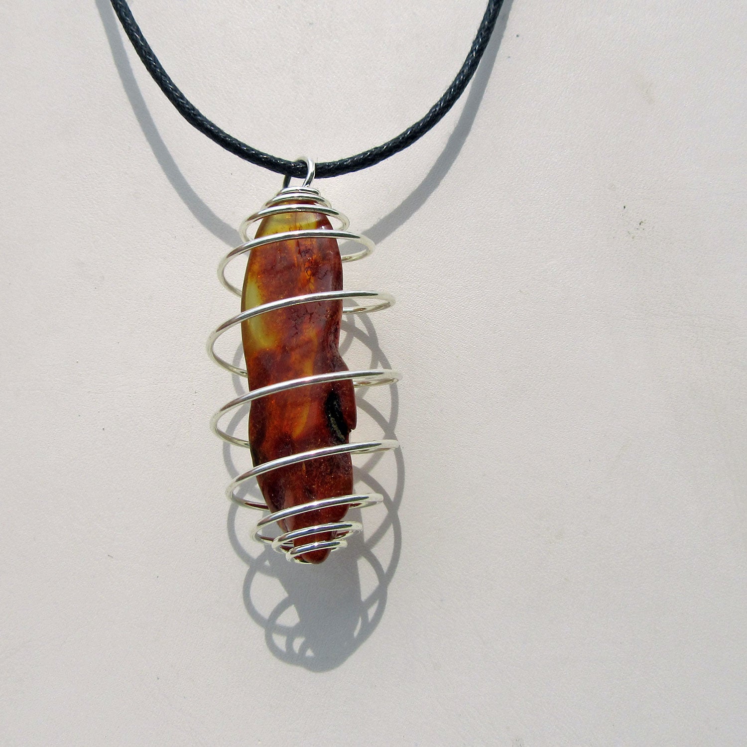 Polierter Bernstein mit versilberter Spirale – Unikat
