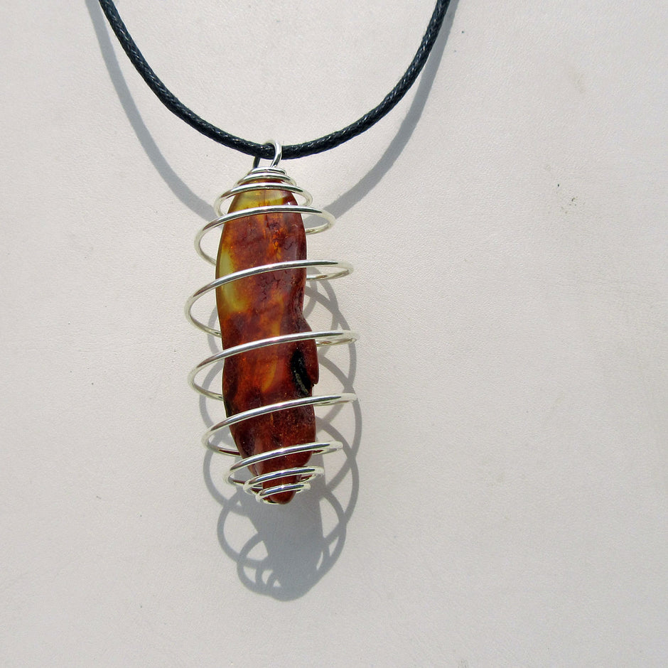 Polierter Bernstein mit versilberter Spirale – Unikat
