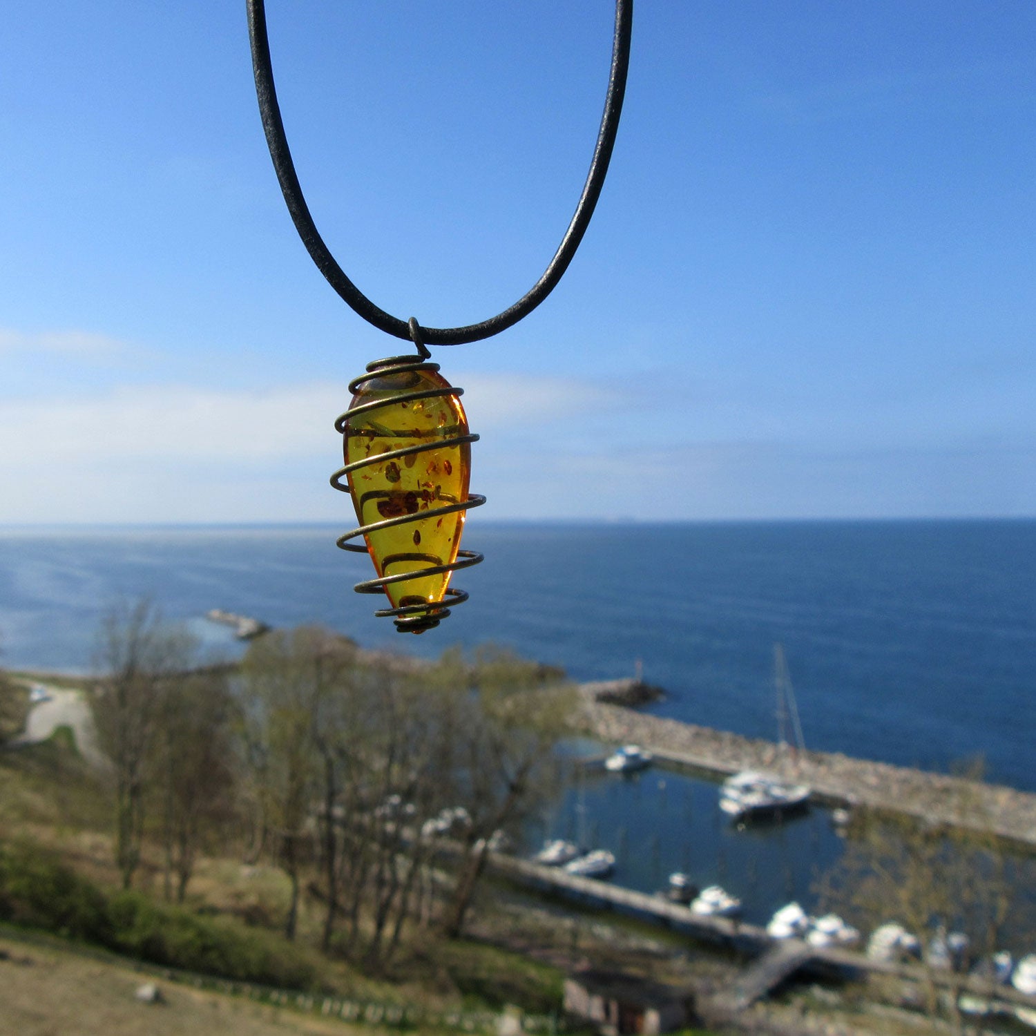 Flaches Bernsteinstück mit Einschlüssen am Lederband