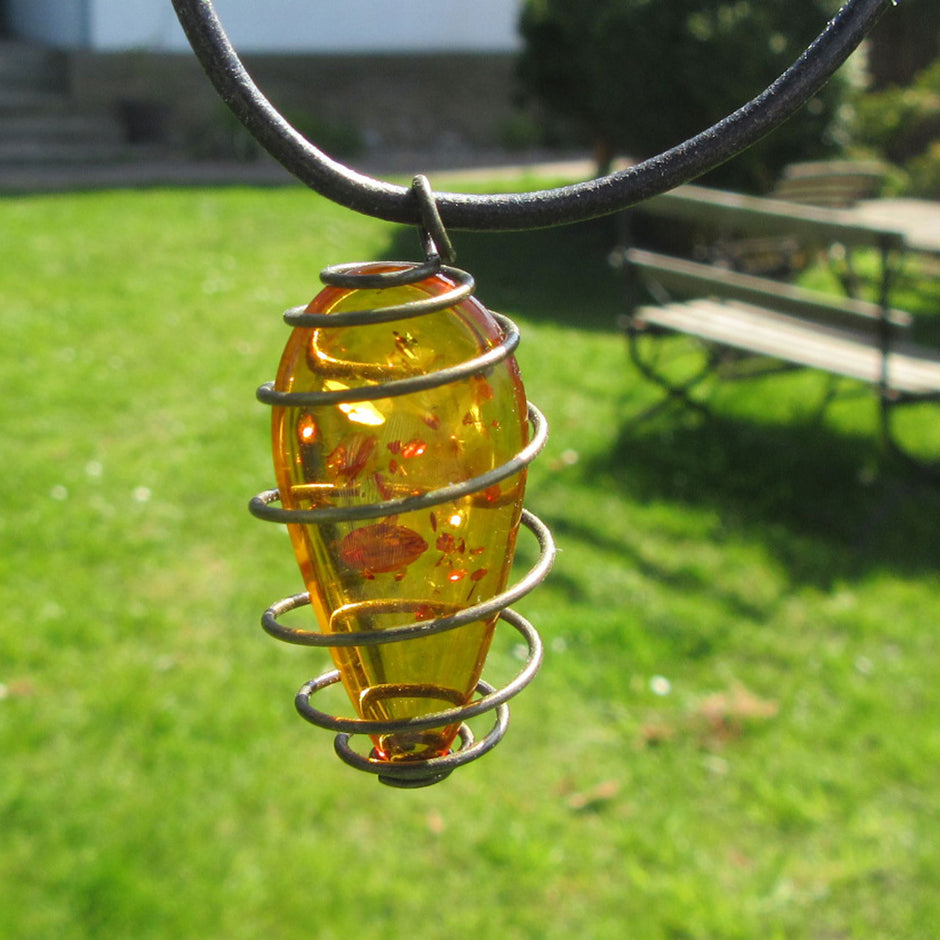 Flaches Bernsteinstück mit Einschlüssen am Lederband