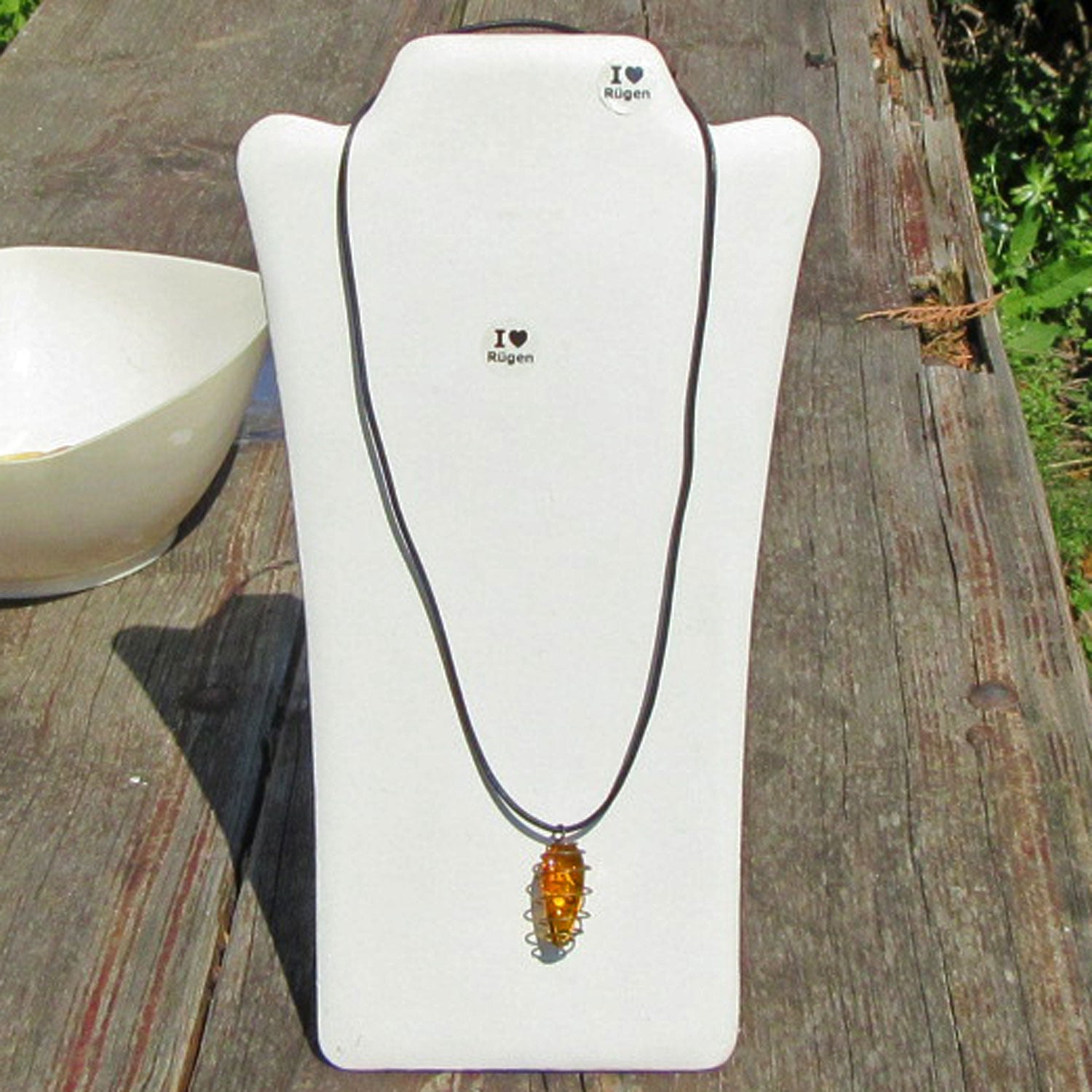 Flaches Bernsteinstück mit Einschlüssen am Lederband