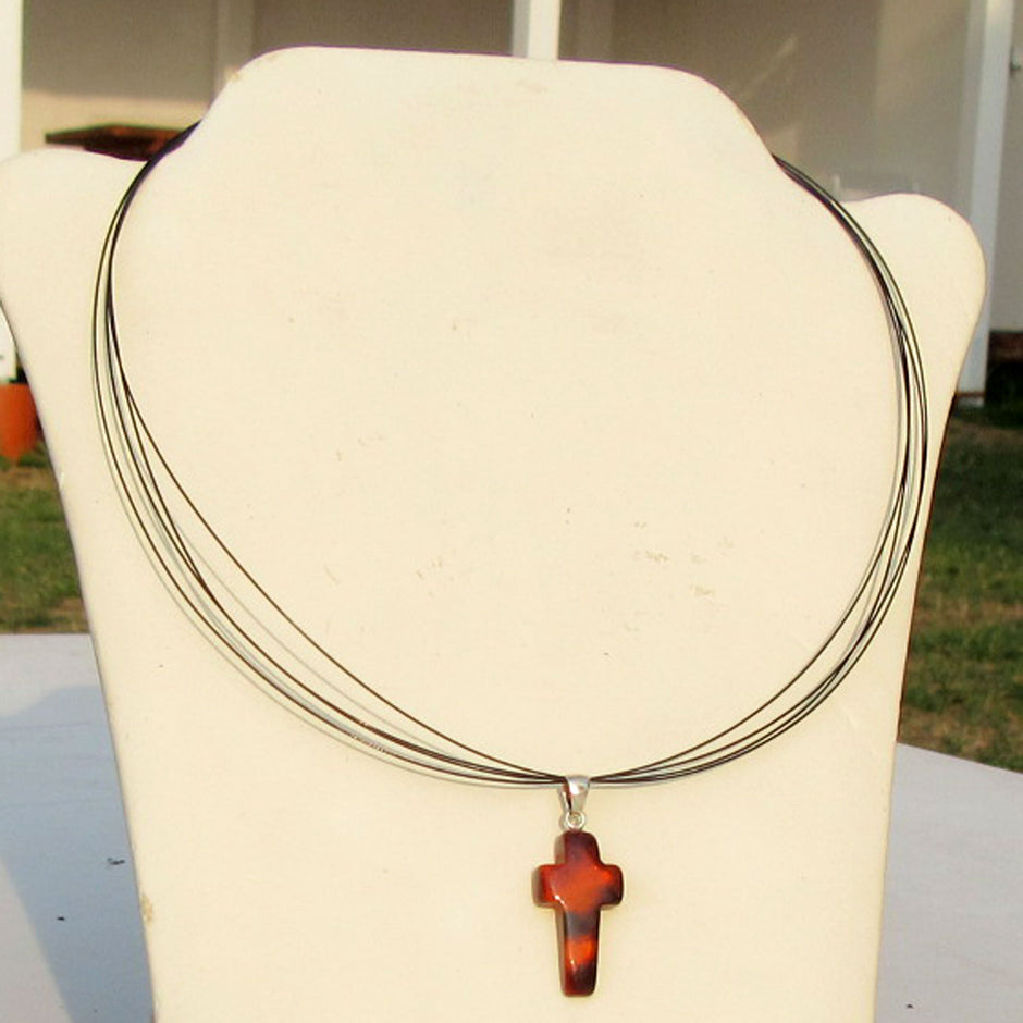 Anhänger in Kreuzform aus kognacfarbenem Bernstein mit Einschlüssen