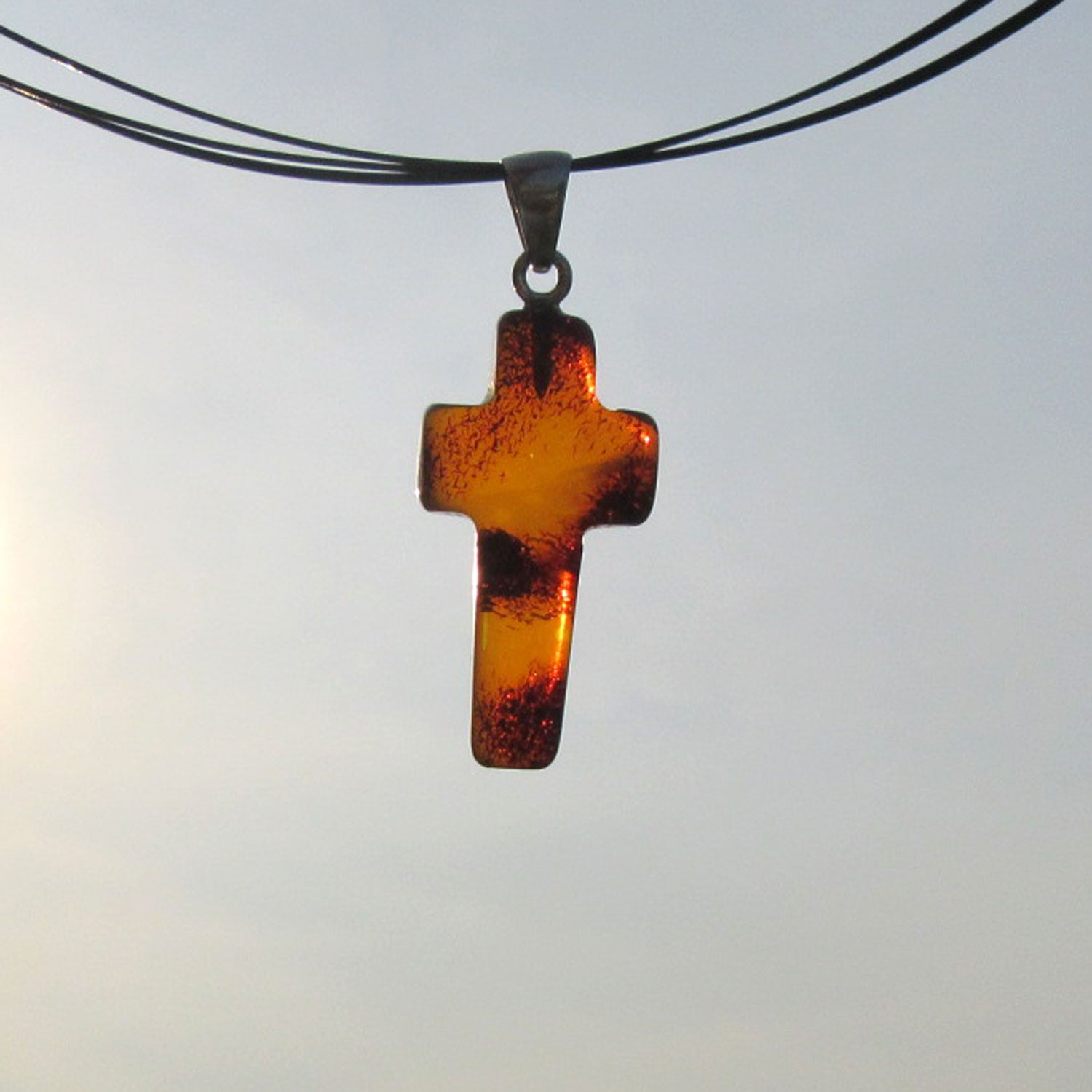 Anhänger in Kreuzform aus kognacfarbenem Bernstein mit Einschlüssen