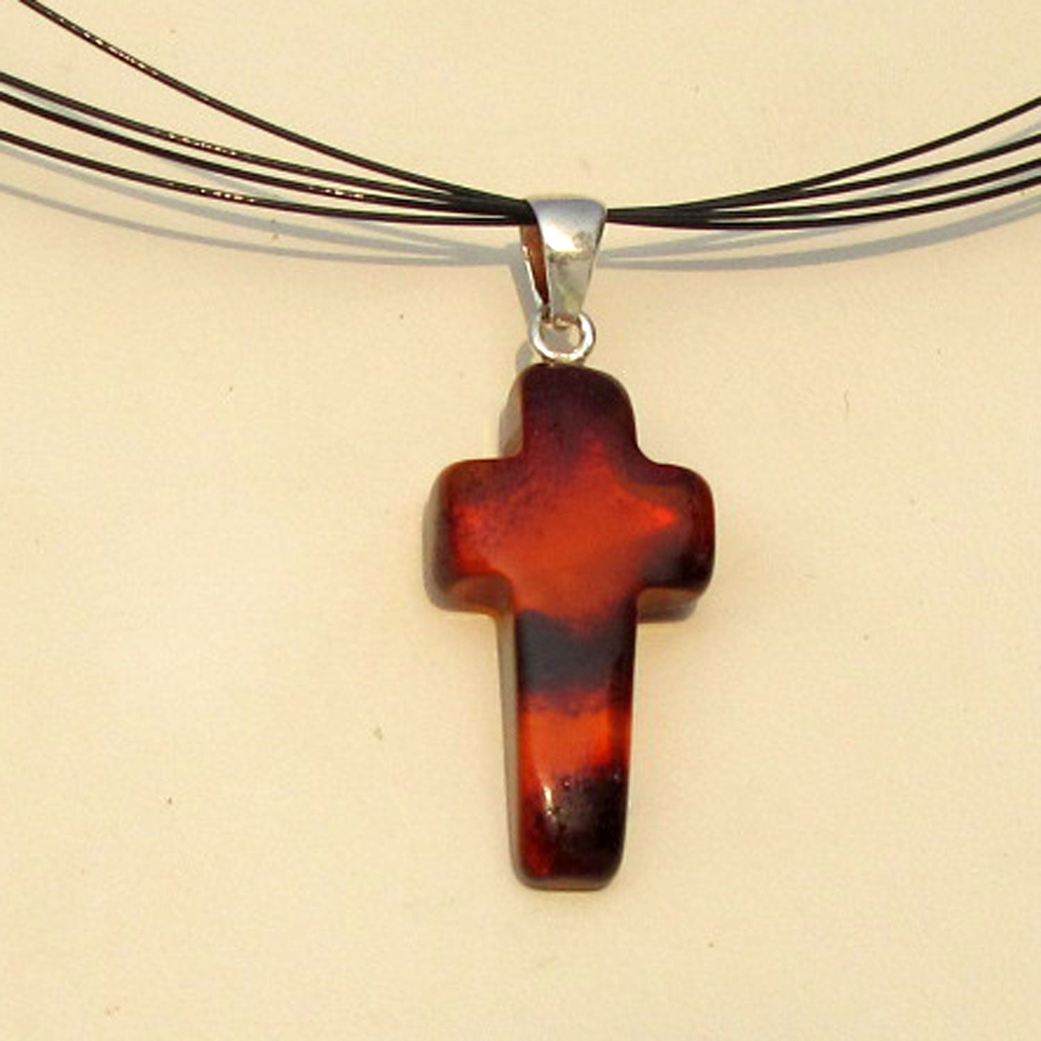 Anhänger in Kreuzform aus kognacfarbenem Bernstein mit Einschlüssen