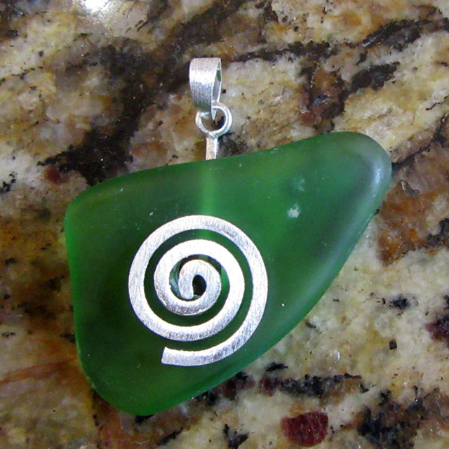 Anhänger aus einem grünem Seeglasstück auf einer gebürsteten Silberspirale