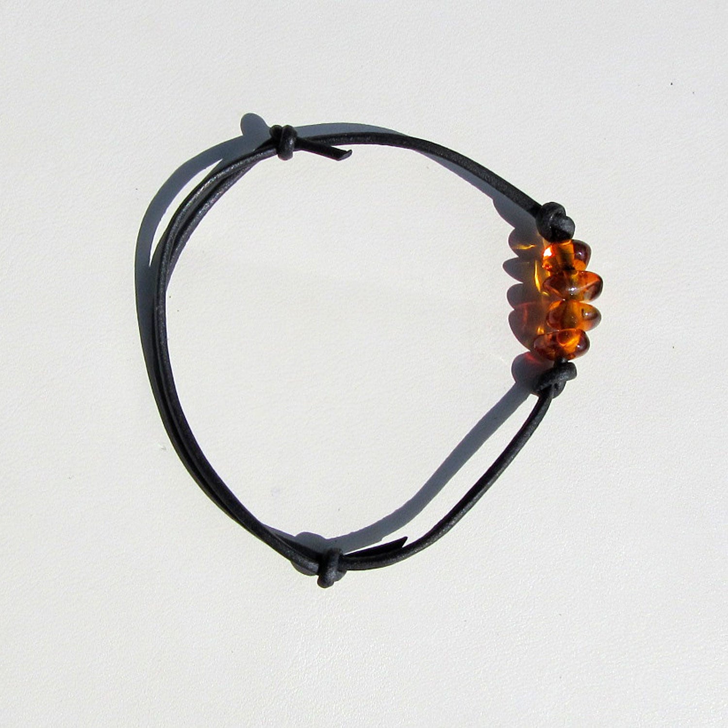 Schwarzes Lederarmband mit vier kleinen kognacfarbenen Bernsteinen