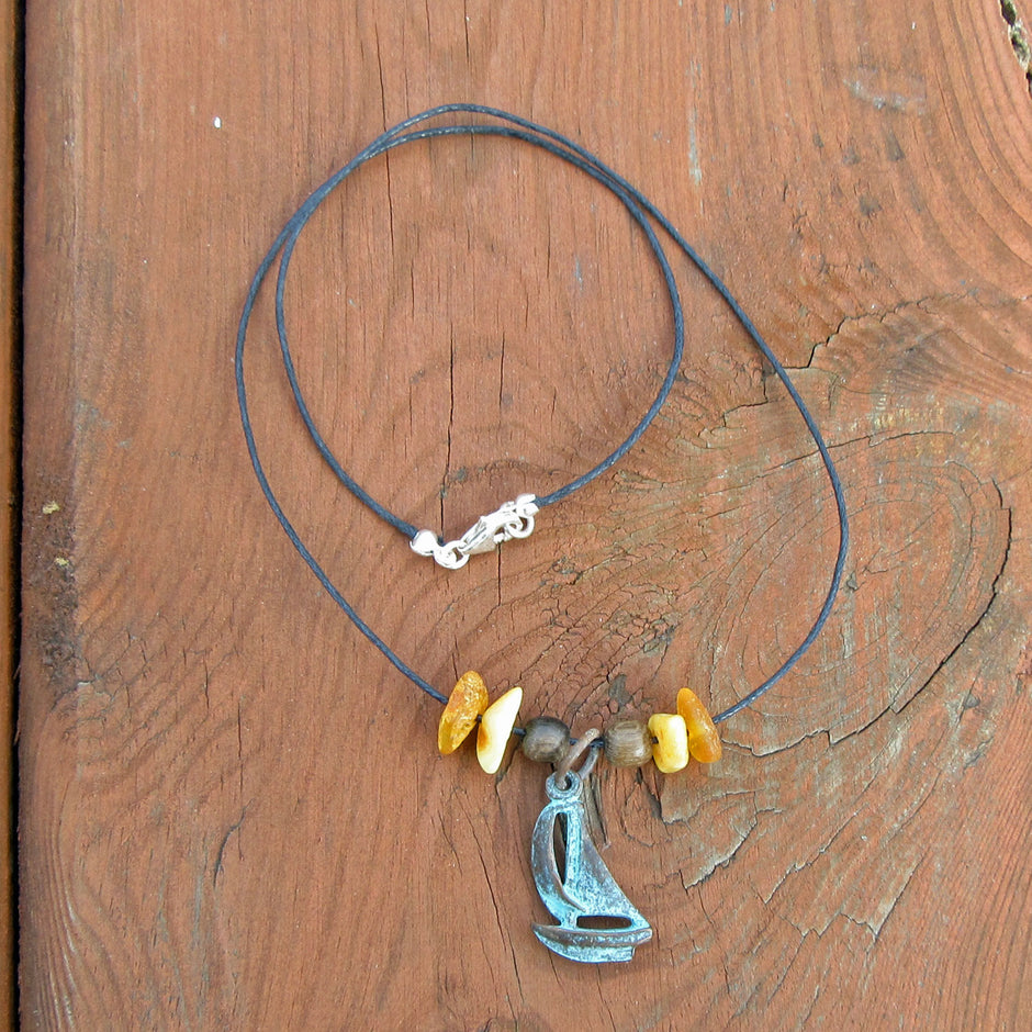 Bernsteine und patiniertes Segelboot am Baumwollcollier