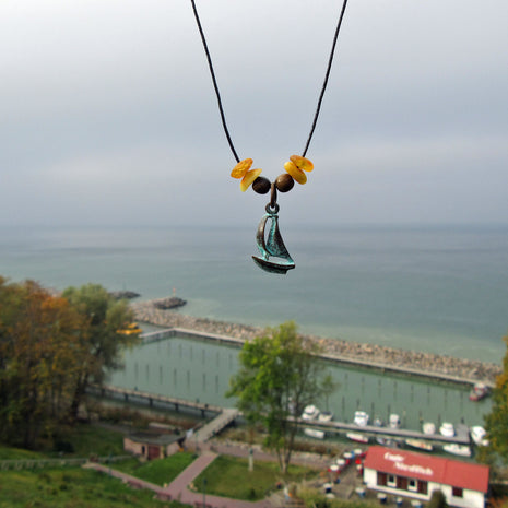 Bernsteine und patiniertes Segelboot am Baumwollcollier