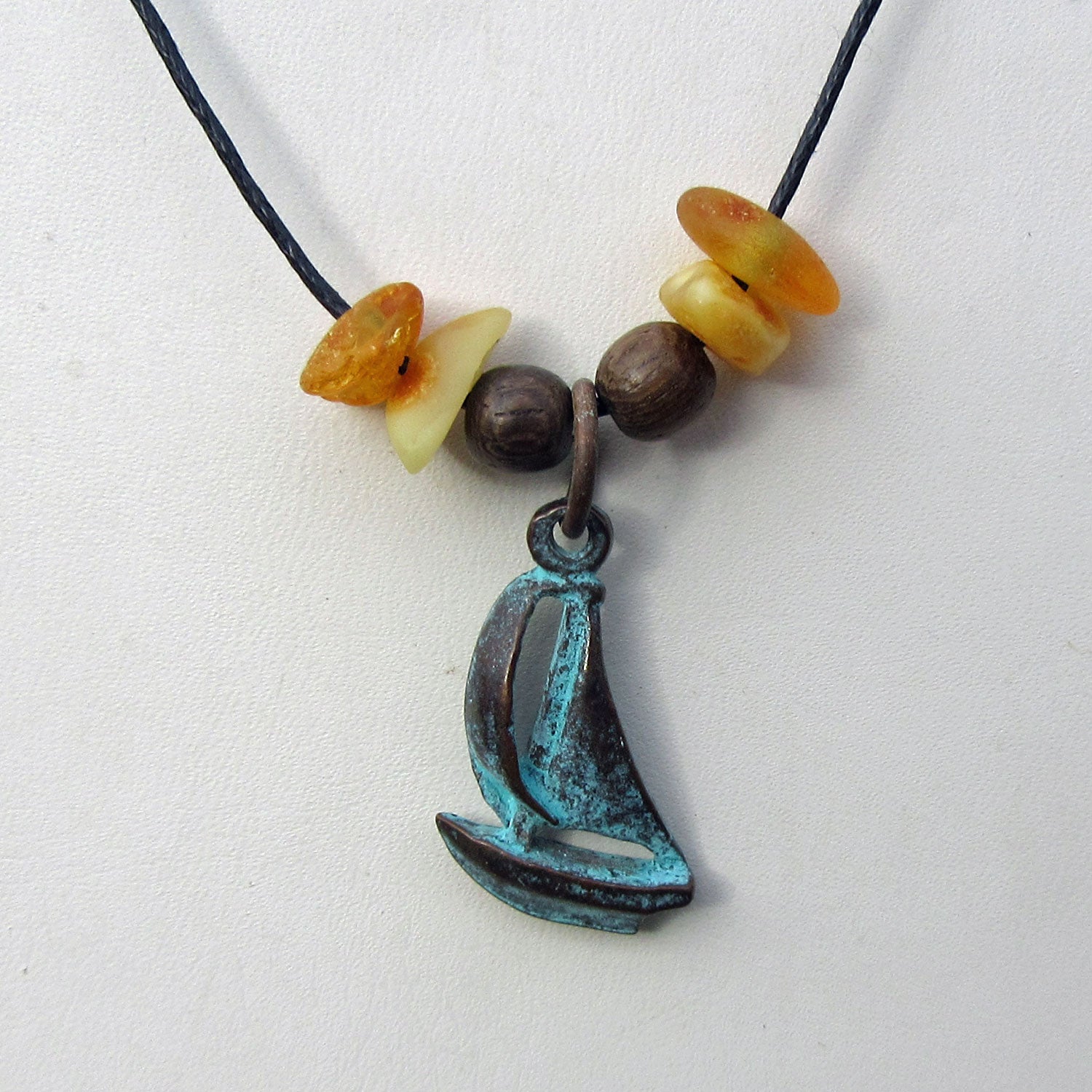 Bernsteine und patiniertes Segelboot am Baumwollcollier