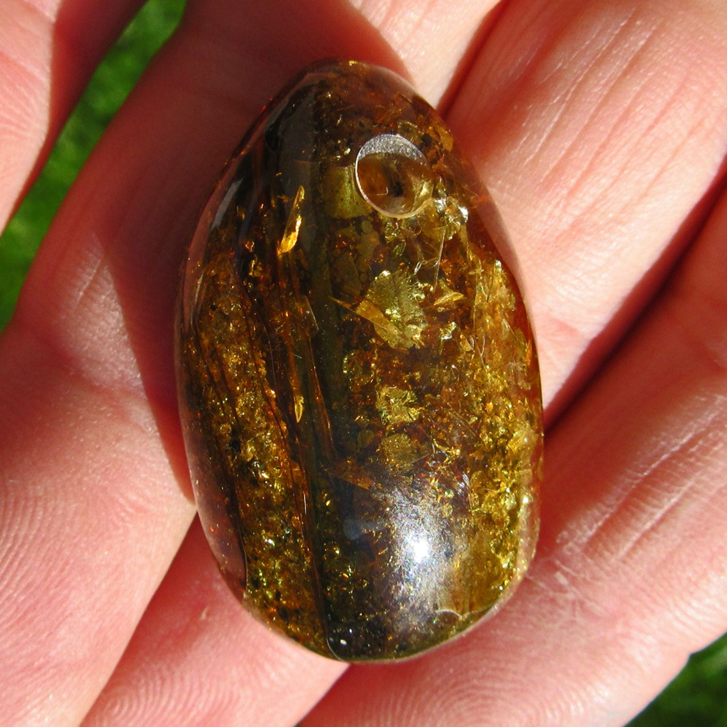 Dunkles, grünliches Bernsteinstück mit Einschlüssen