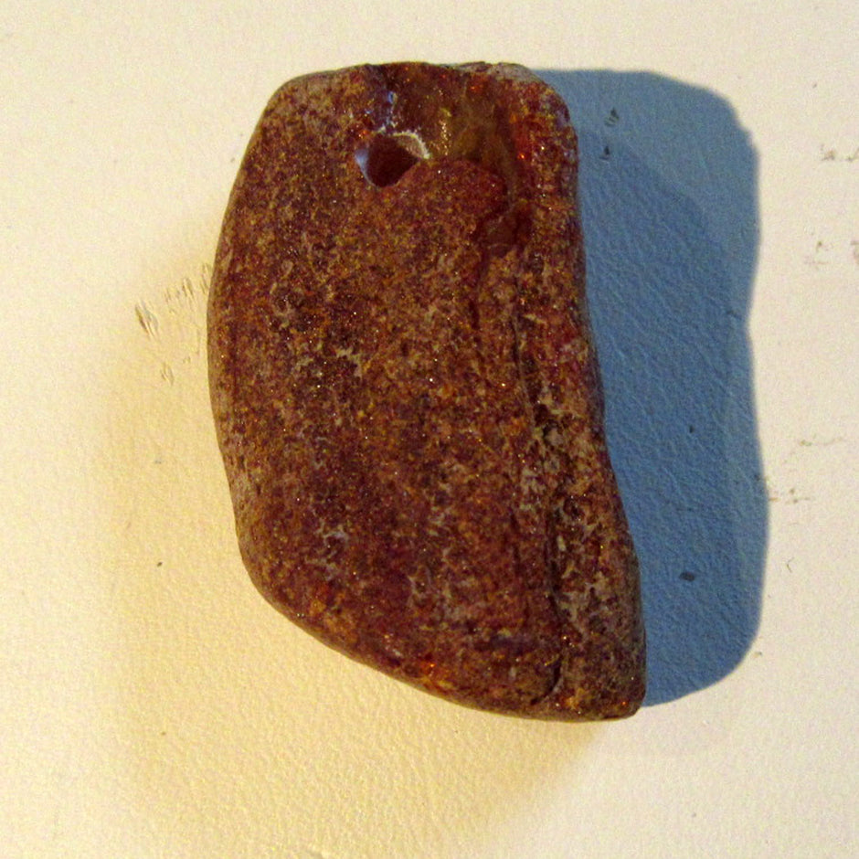 Dunkles Bernsteinstück, unpoliert und gebohrt