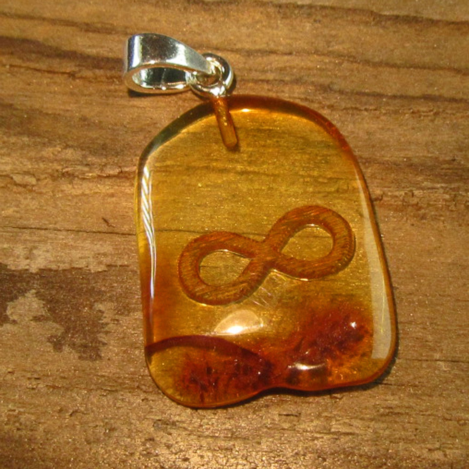 Polierter Bernsteinhänger mit graviertem Unendlichkeitssymbol