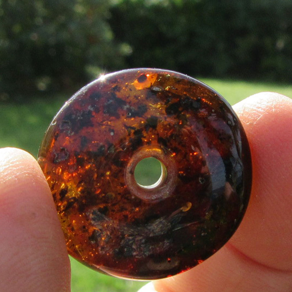 Dunkler Bernsteindonut mit Einschlüssen, rund geschliffen