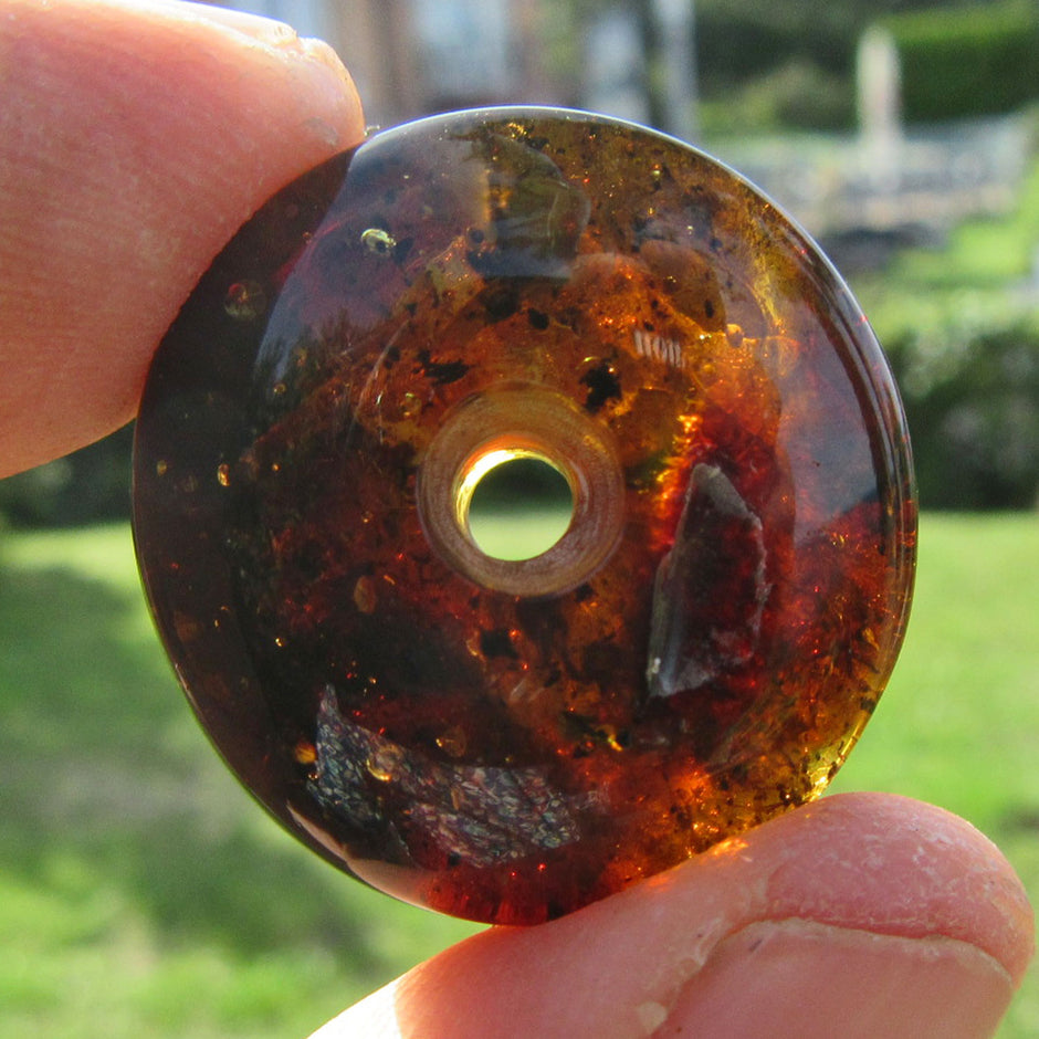 Dunkler Bernsteindonut mit Einschlüssen, rund geschliffen