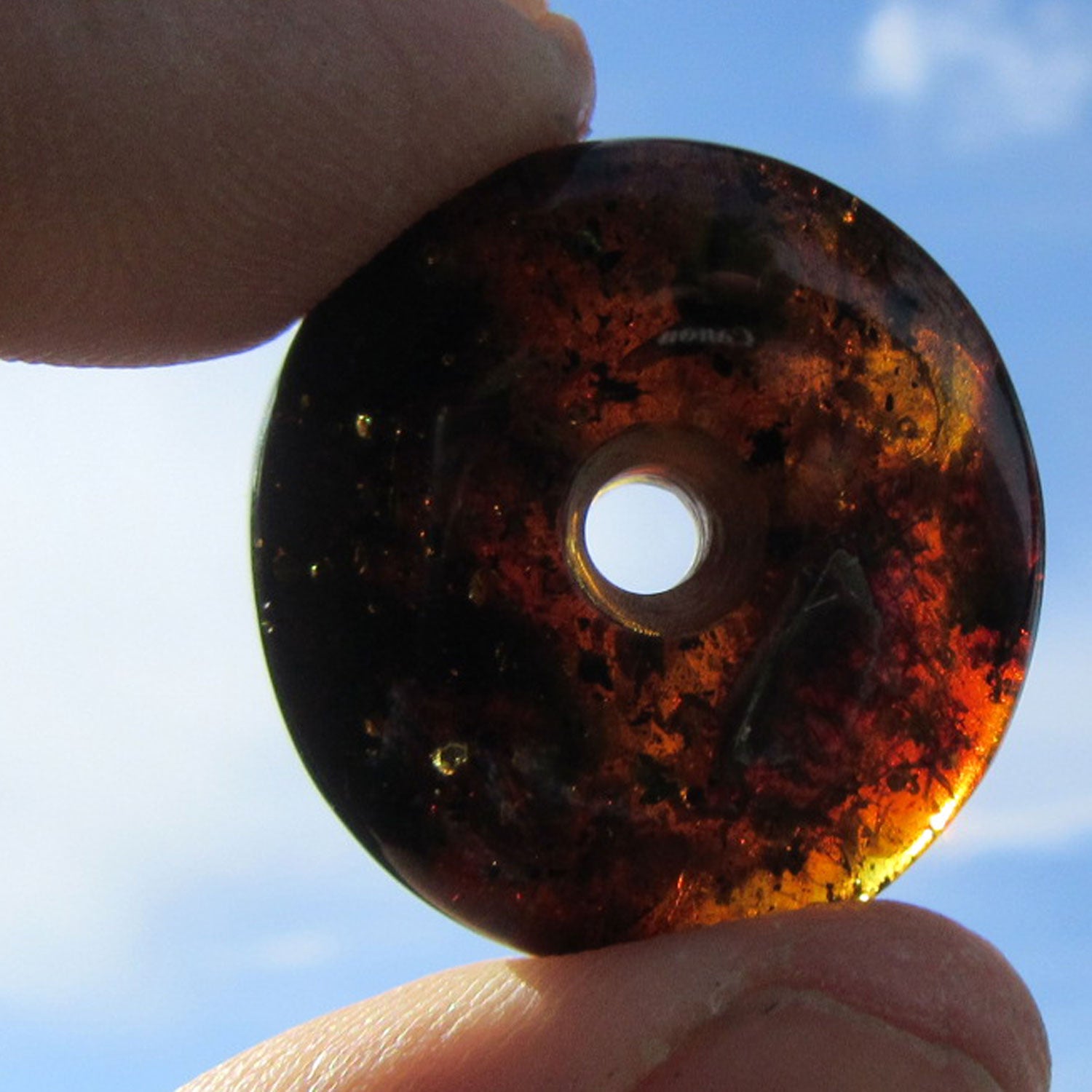 Dunkler Bernsteindonut mit Einschlüssen, rund geschliffen