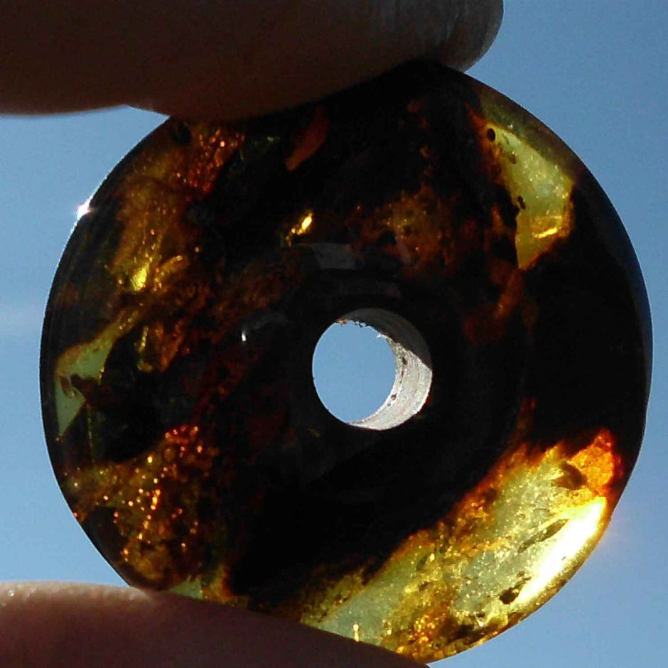 Polierter Bernsteindonut mit natürlichen Einschlüssen