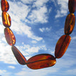 Lange Kette aus kirschrot-braunen Bernsteinoliven, flach