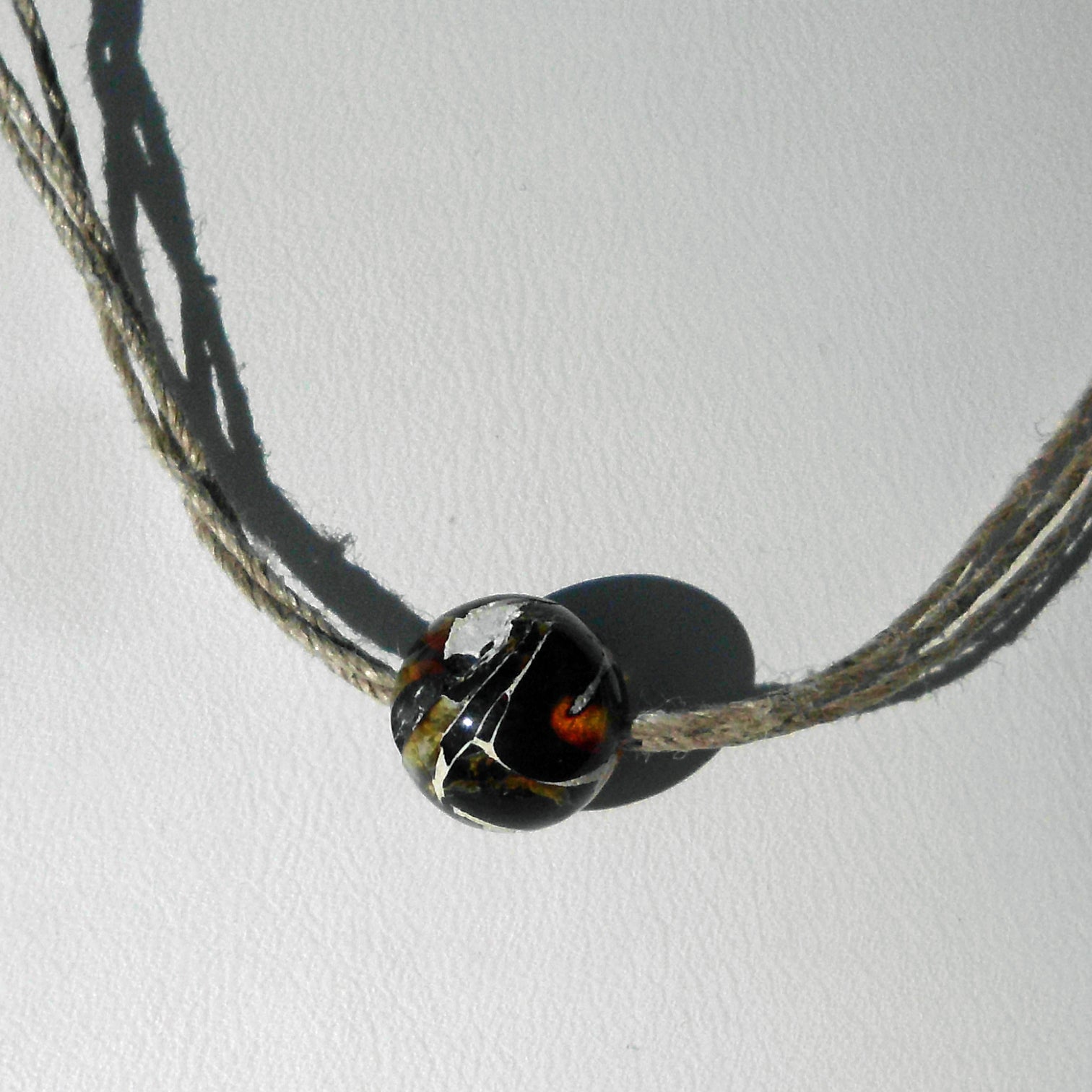 Einzelstück: Kleine Mosaikbernsteinperle auf Hanfcollier