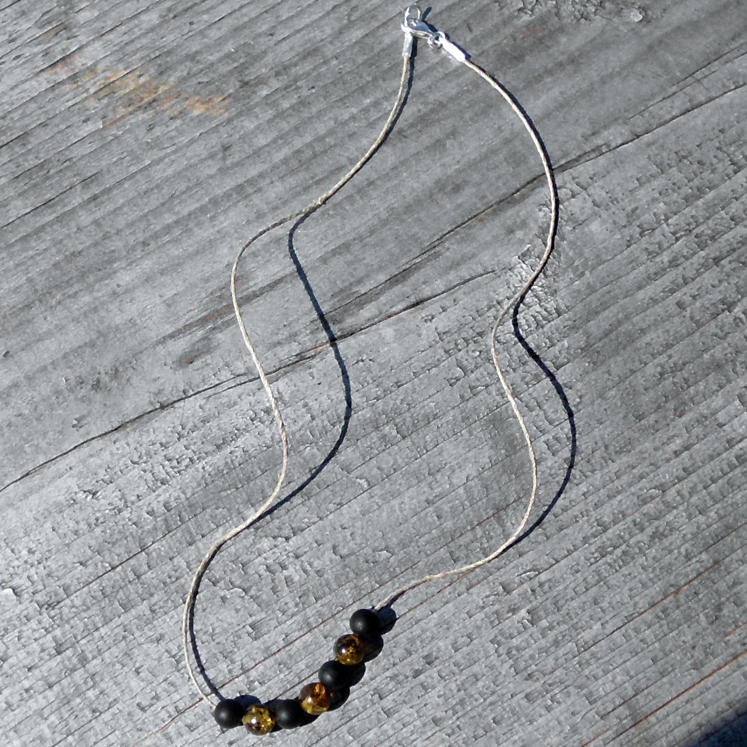 Polierte Bernsteinperlen und schwarze Glasperlen auf Hanfband