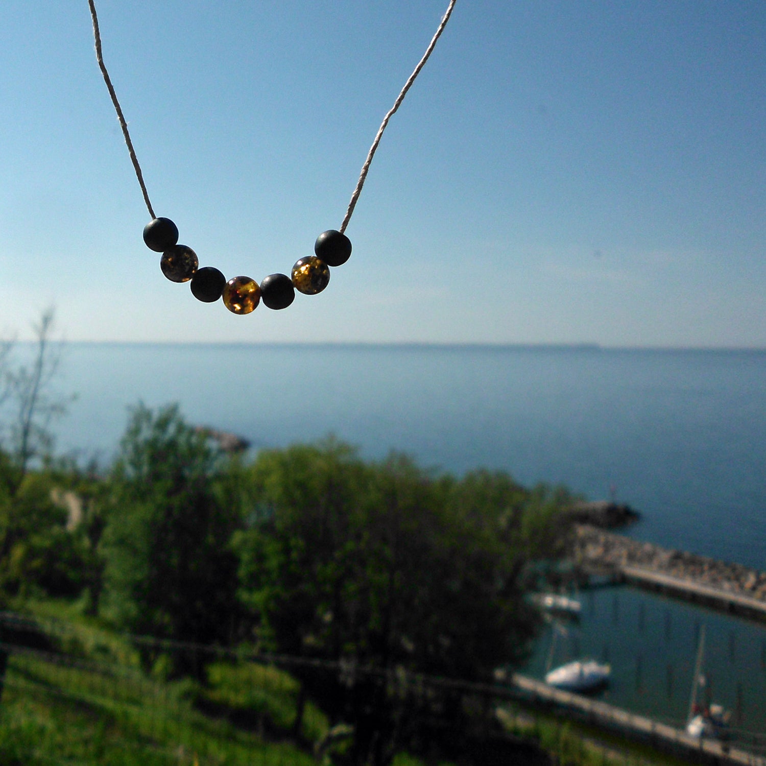 Polierte Bernsteinperlen und schwarze Glasperlen auf Hanfband