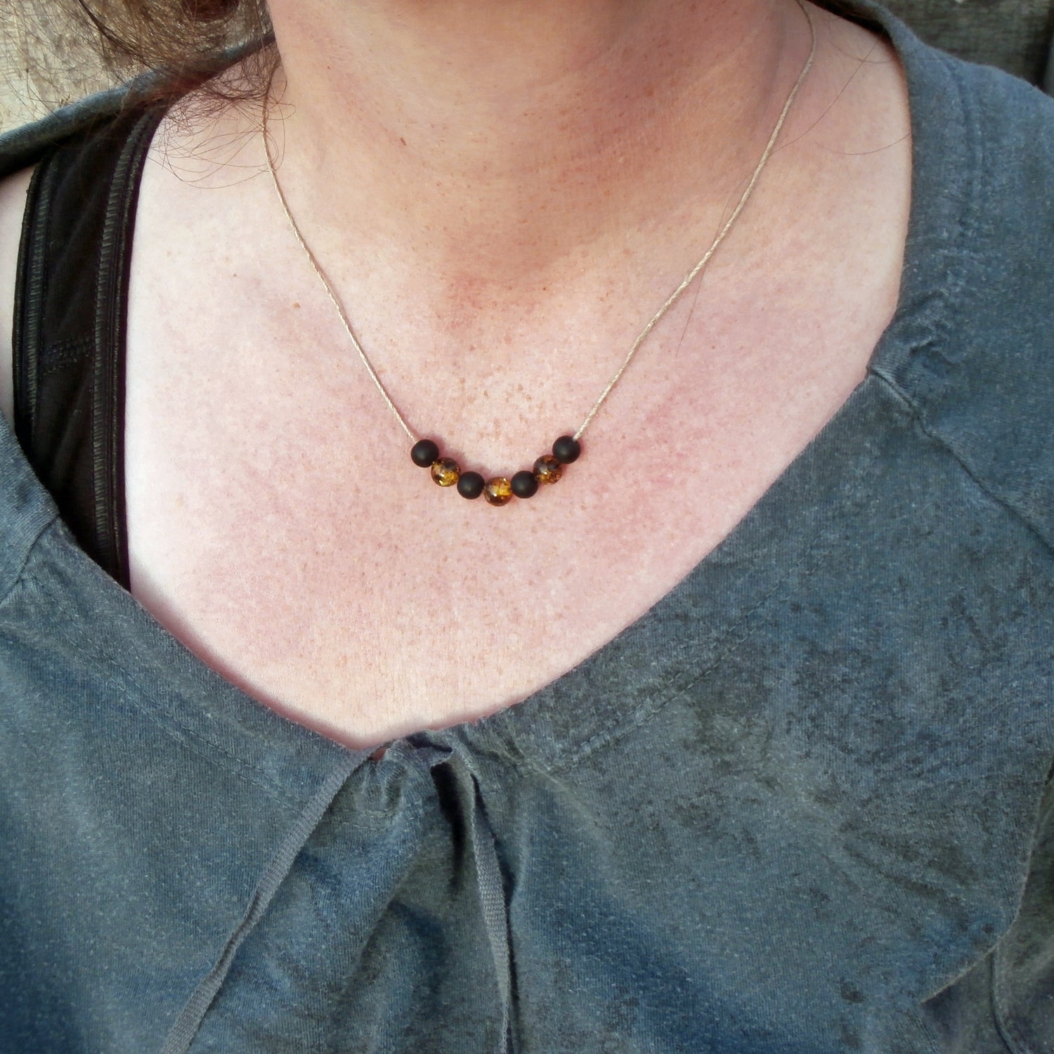 Polierte Bernsteinperlen und schwarze Glasperlen auf Hanfband