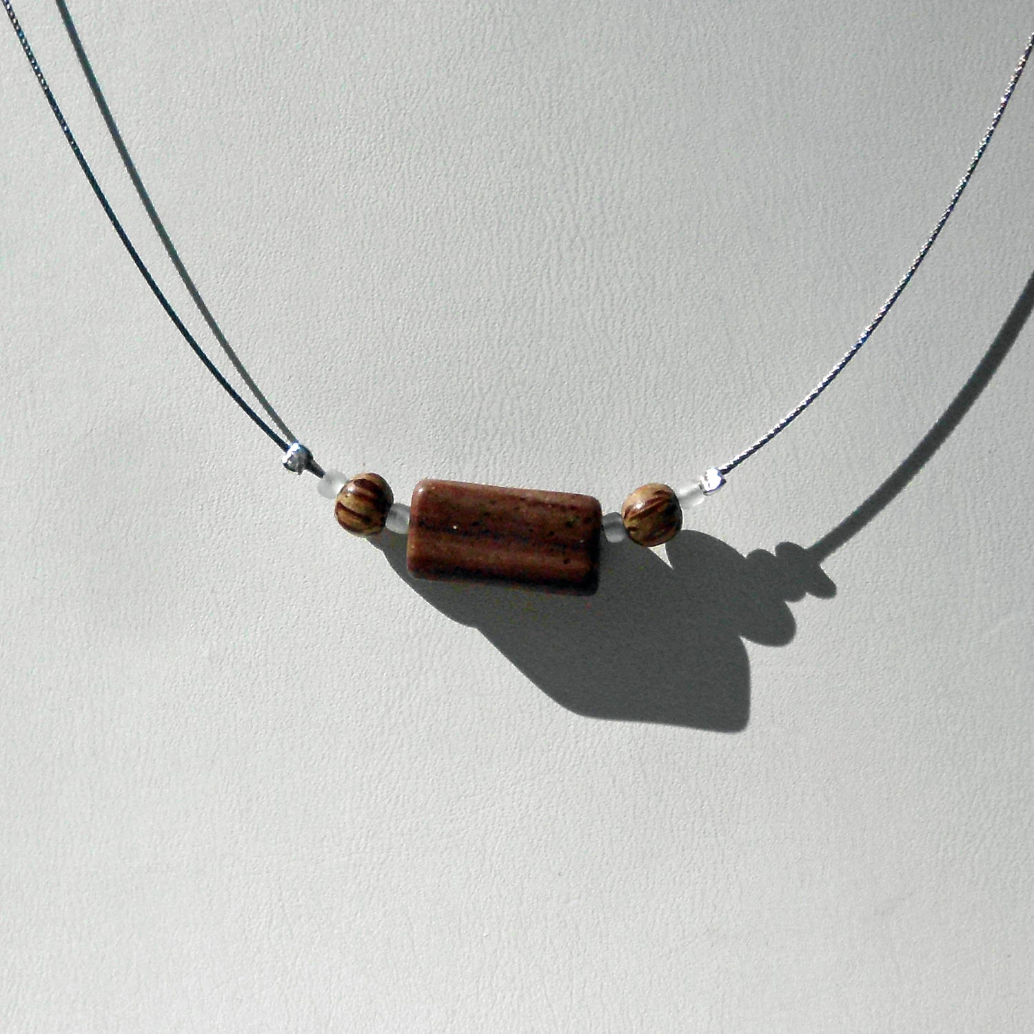 Polierter Sandsteinquader am Drahtcollier mit Perlen