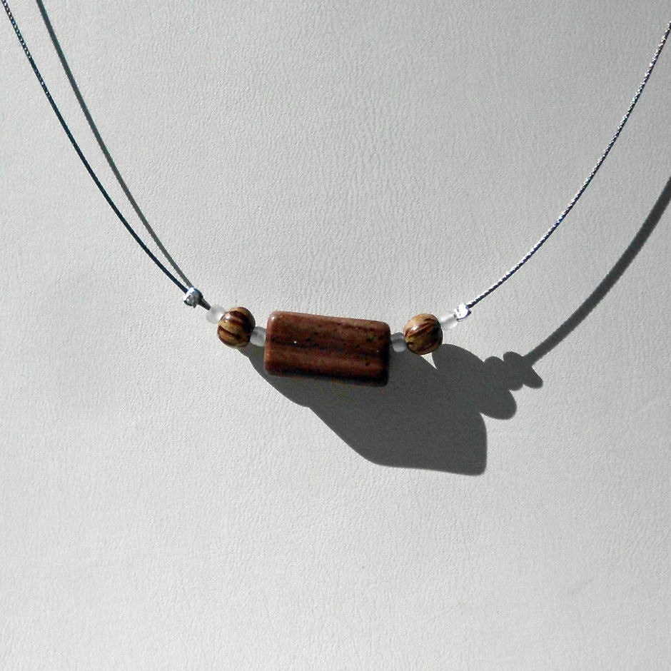 Polierter Sandsteinquader am Drahtcollier mit Perlen