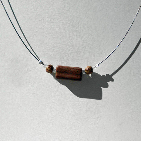 Polierter Sandsteinquader am Drahtcollier mit Perlen