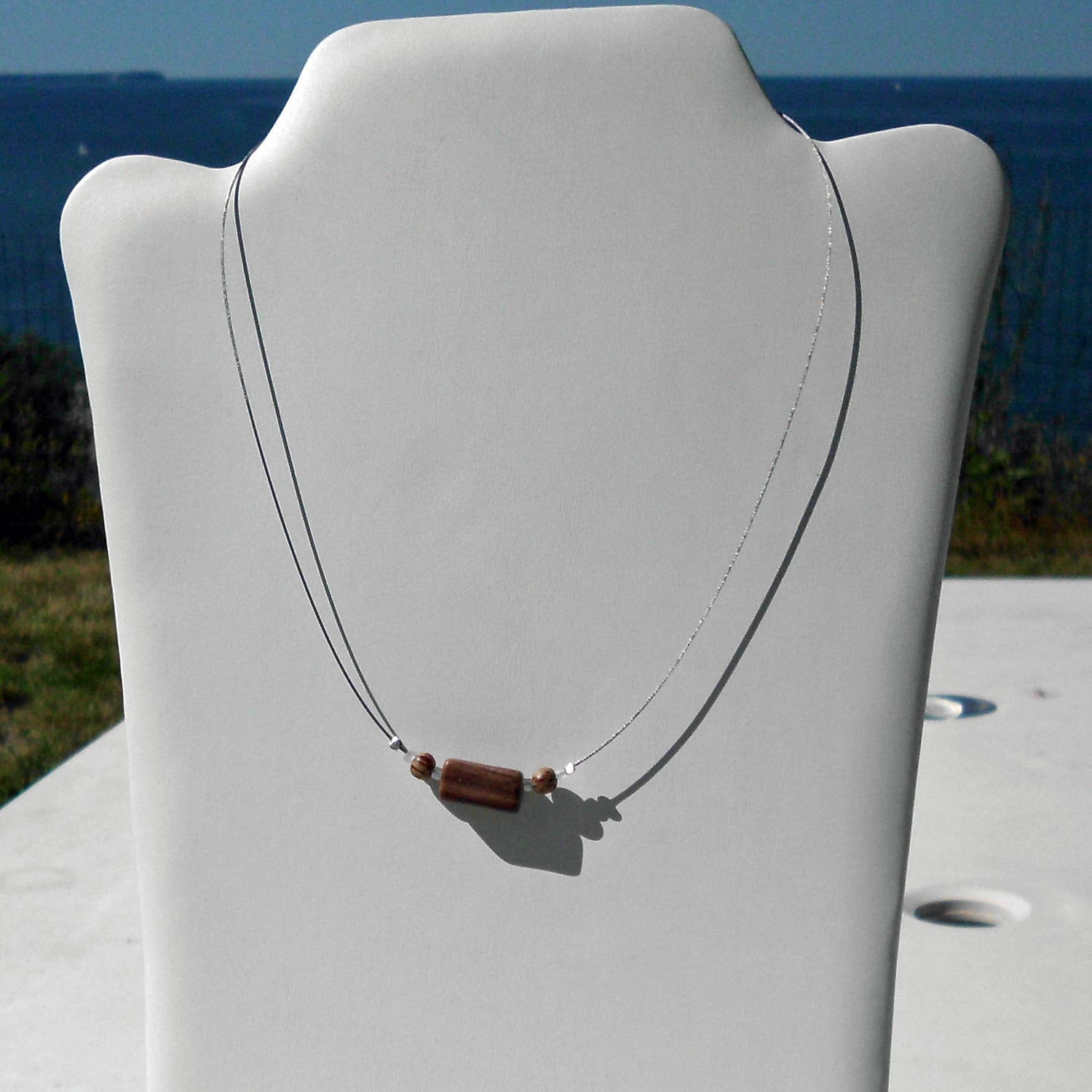 Polierter Sandsteinquader am Drahtcollier mit Perlen