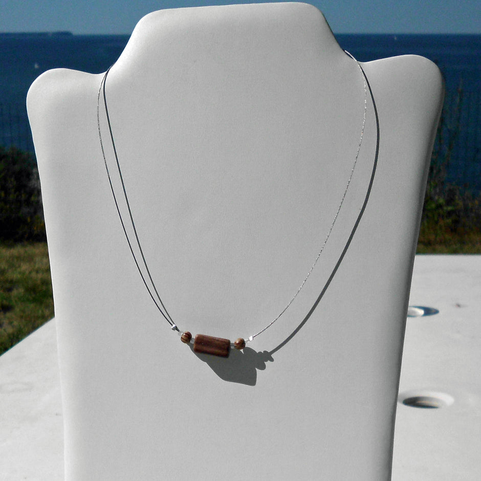 Polierter Sandsteinquader am Drahtcollier mit Perlen