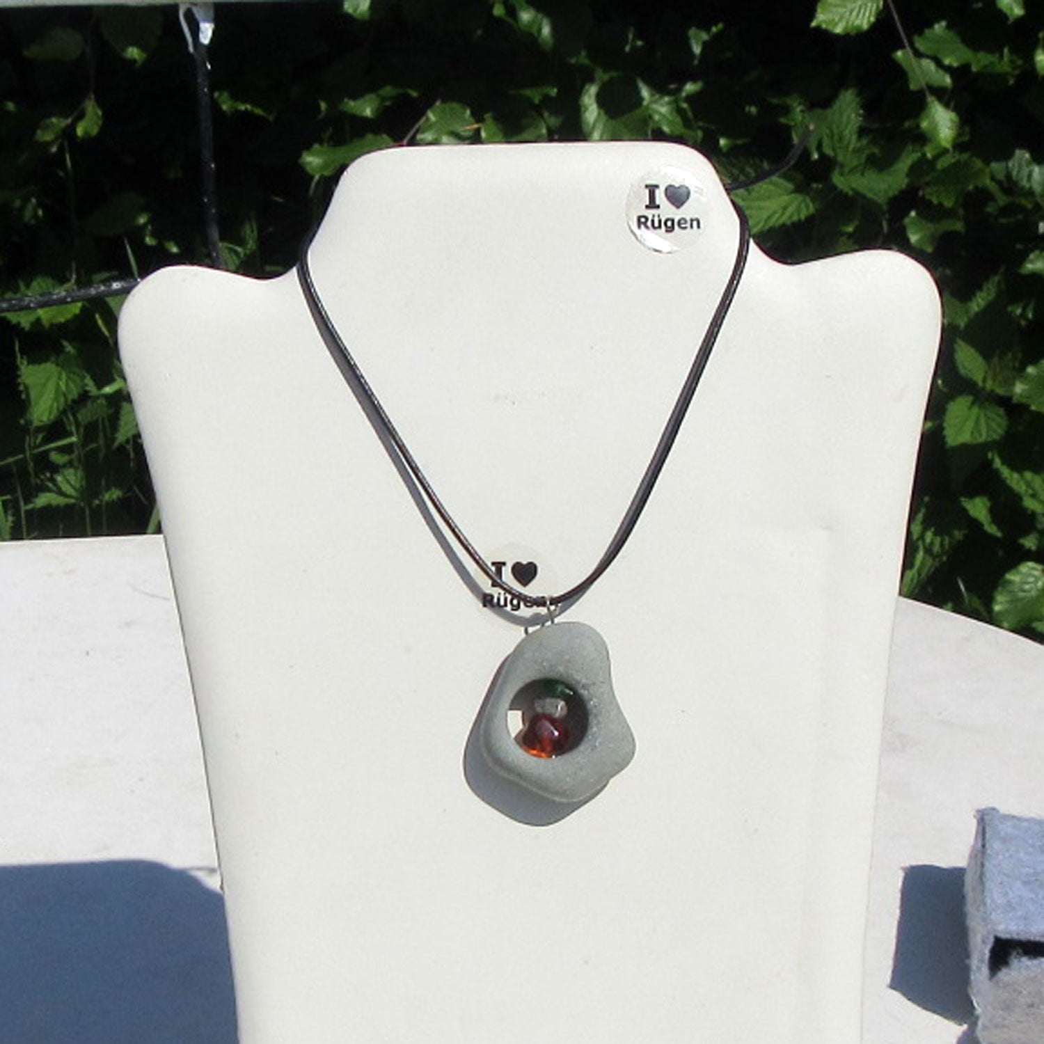 Bernsteinperle mit Seeglas und Silber im Kiesel von Rügen