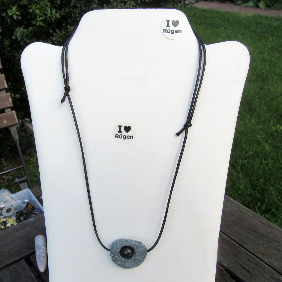 Polierte Feuersteinperle in unpoliertem Kiesel von Rügen