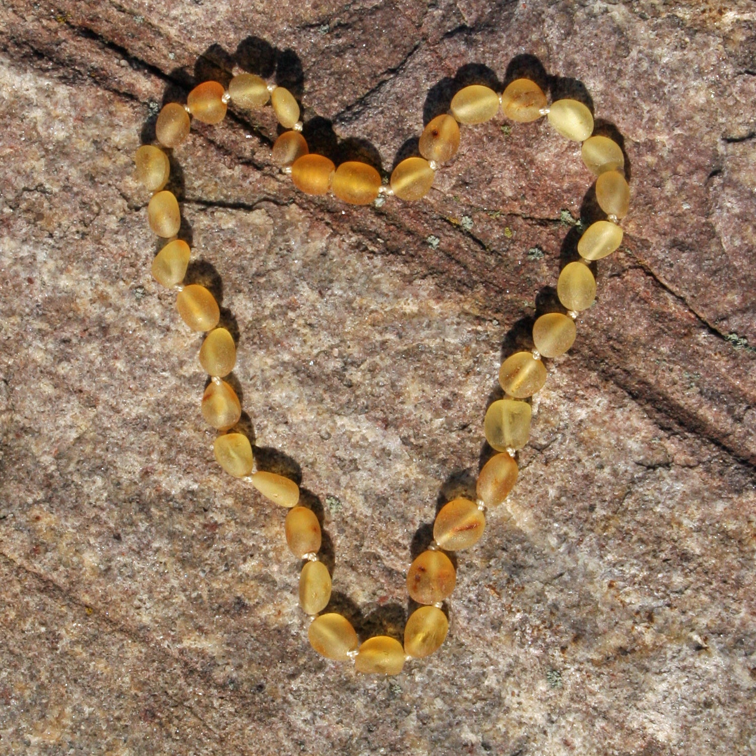 Zahnungskette in Olivenform aus unpoliertem Bernstein