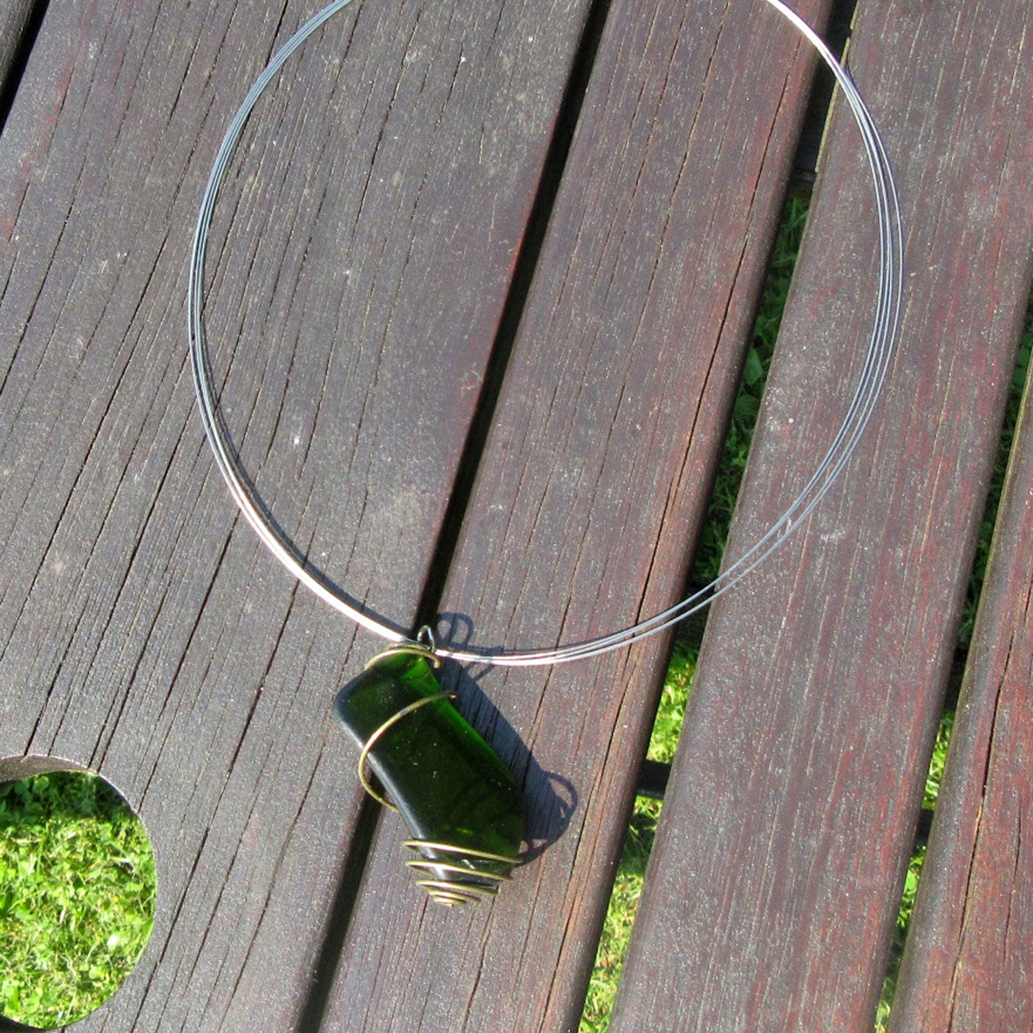 Grosser Anhänger aus grünem Seeglas in einer messingfarbenen Spirale