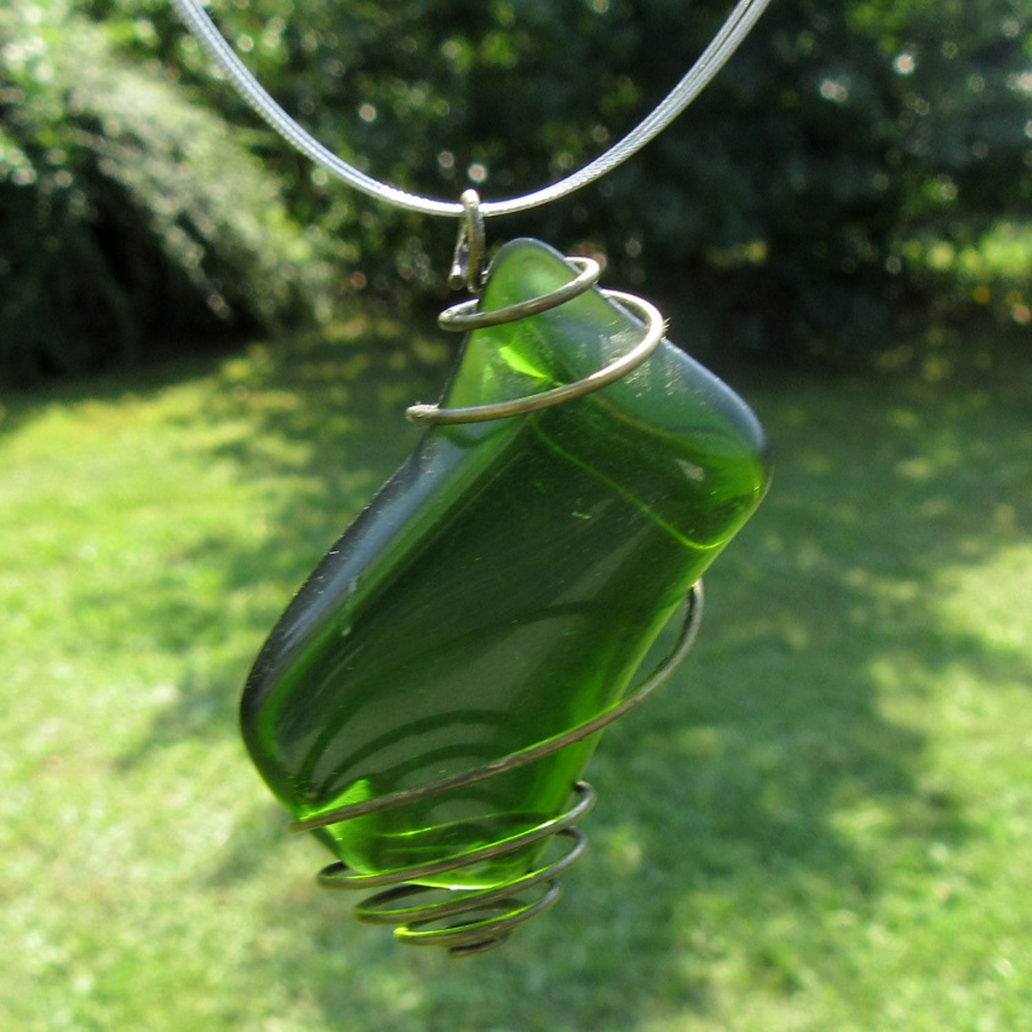 Grosser Anhänger aus grünem Seeglas in einer messingfarbenen Spirale