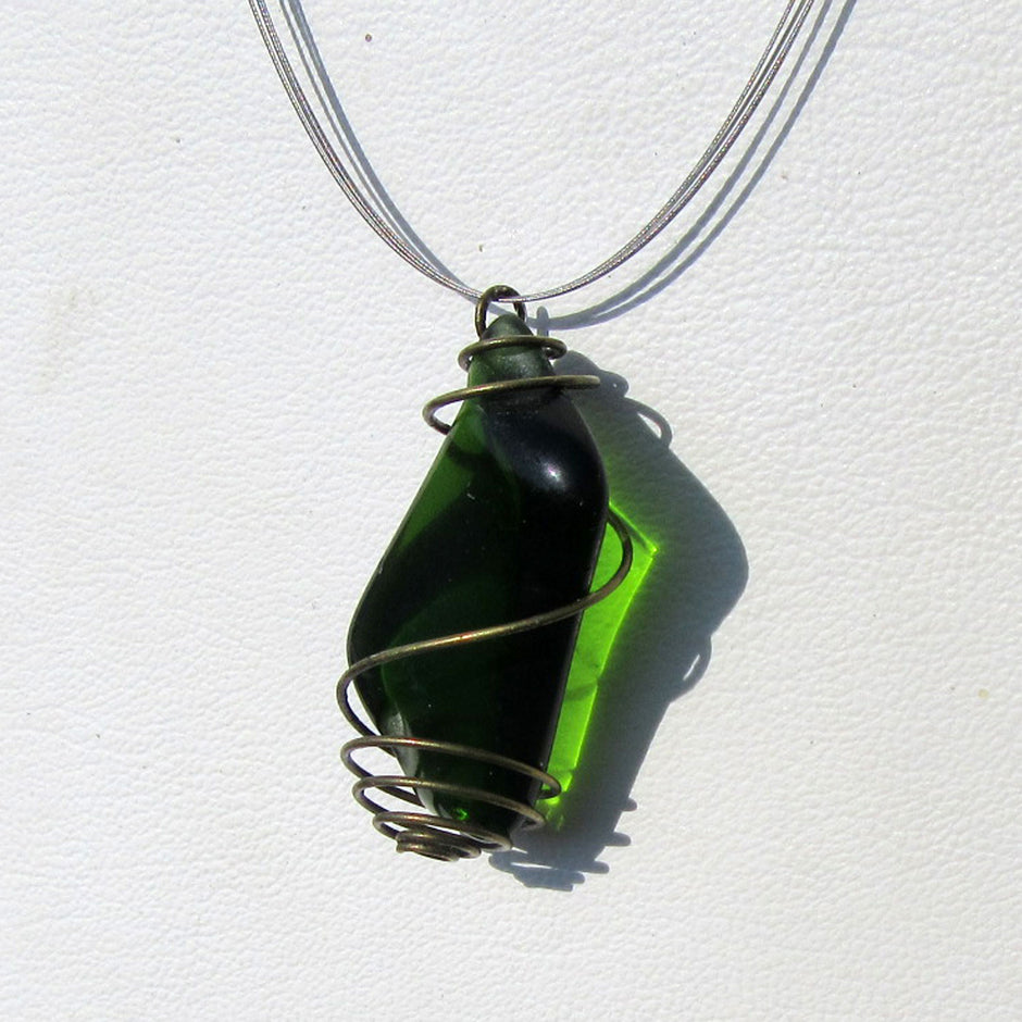 Grosser Anhänger aus grünem Seeglas in einer messingfarbenen Spirale