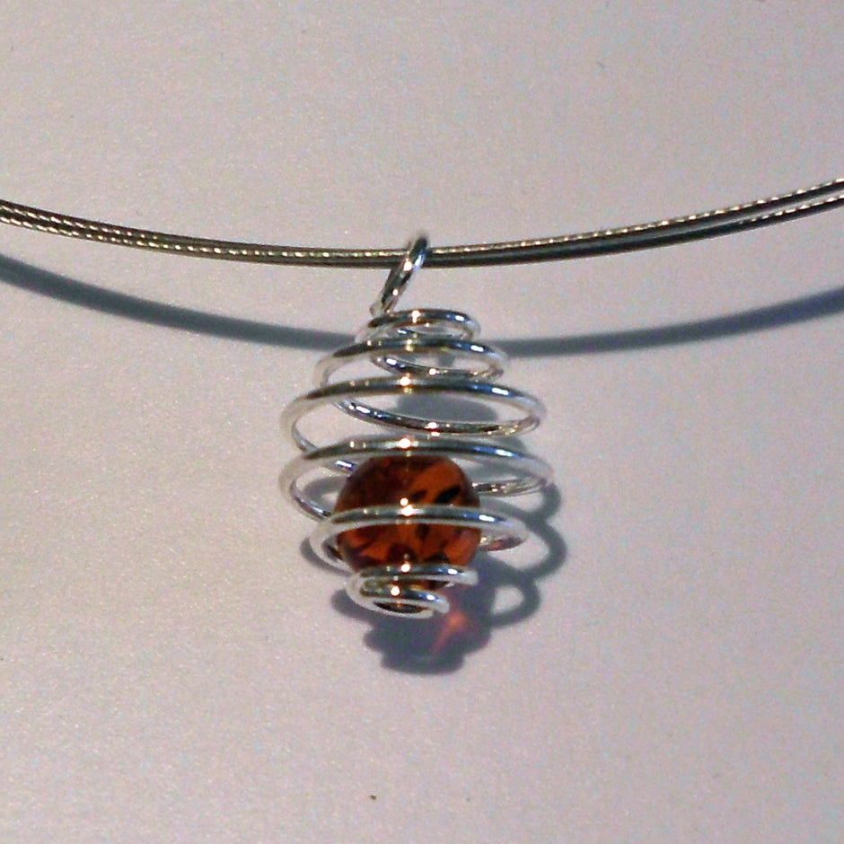Bernsteinkugel in silberfarbener Spirale – Unikat